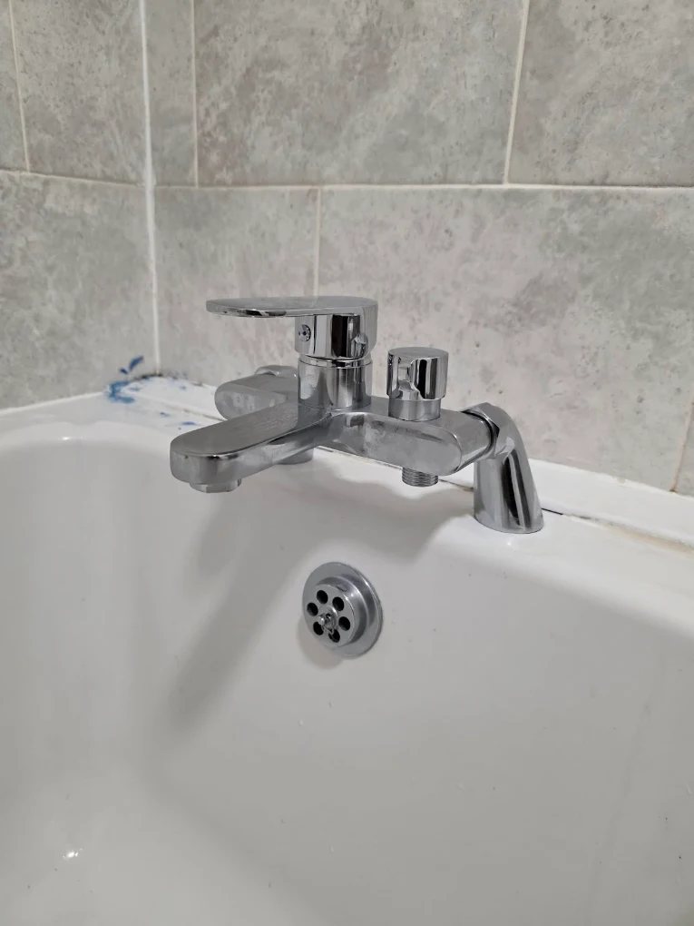 Chrome bath and shower mixer tap fitted to a white bath with tiled surround